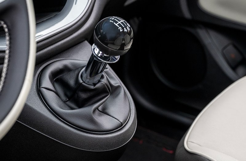Car gear stick with a manual transmission lever and black leather covering.