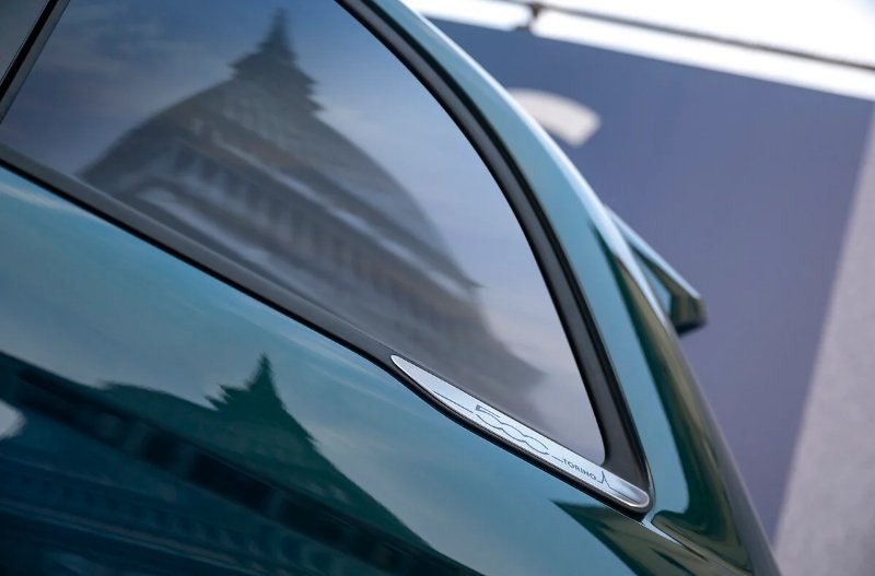 Close-up of a car with a building reflected in the window.