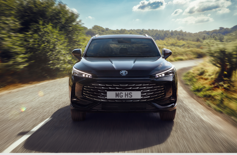 Front view of a black MG HS car driving on a country road.